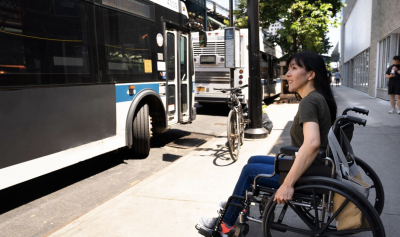 Woman in a wheelchair waiting at a bus stop